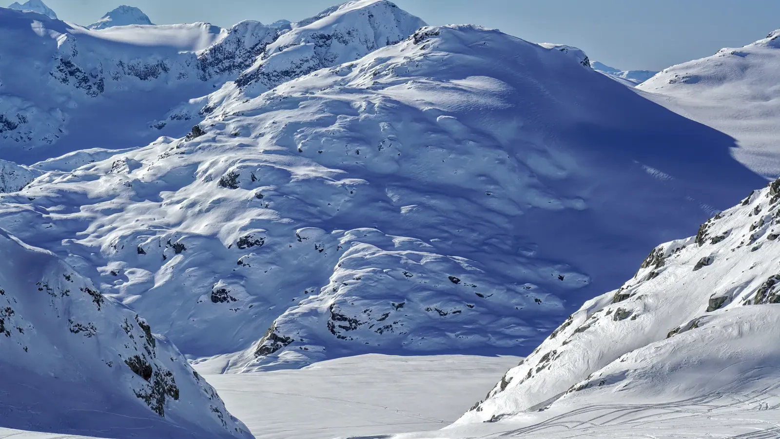 A broad crevassed lobe of the Pemberton Icefield spilling between rock ridges below snow covered Coast Mountain peaks