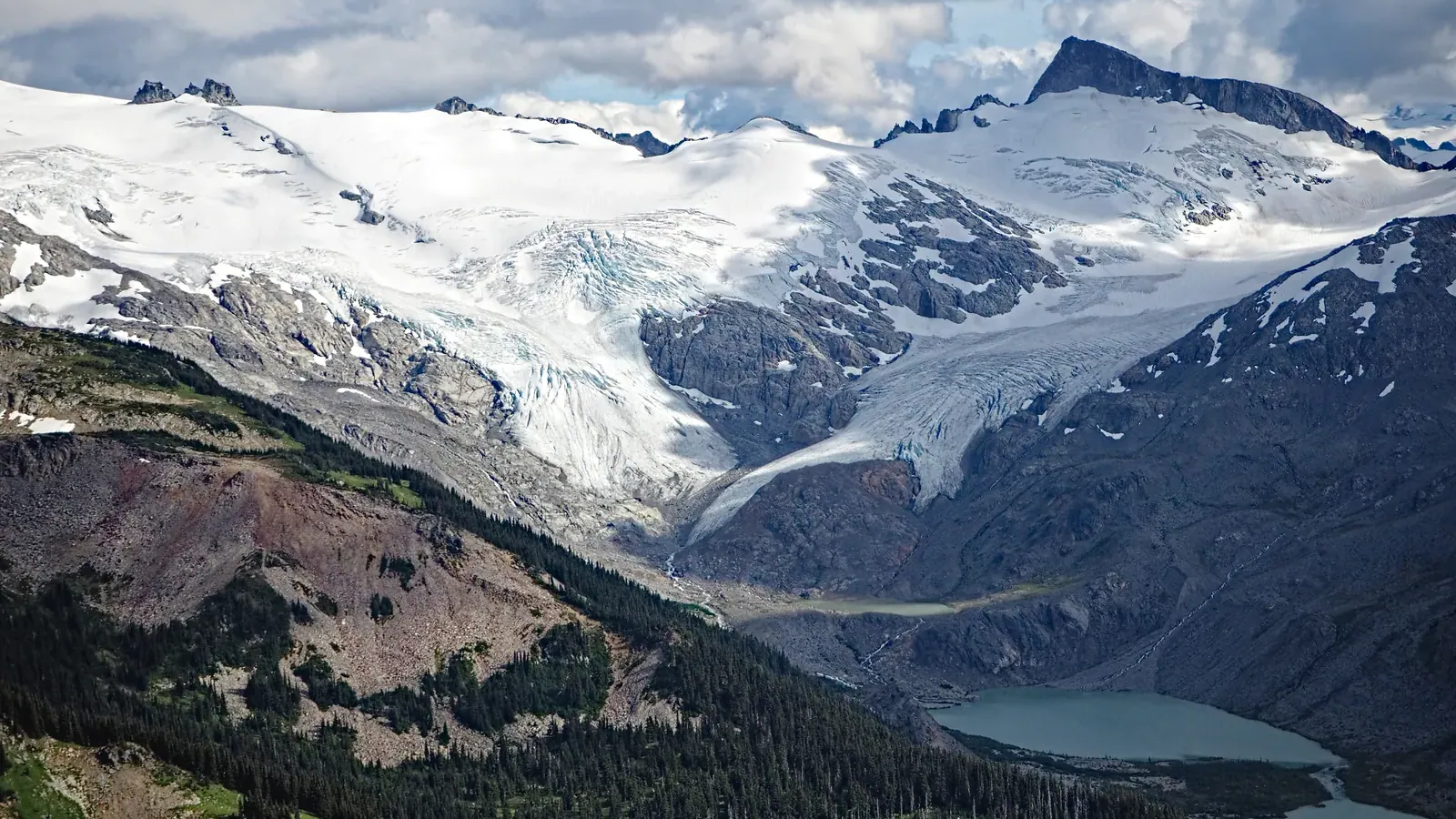 Sphinx Glacier spilling from an icefield down bare rock toward an arm of Garibaldi Lake, seen from Panorama Ridge.