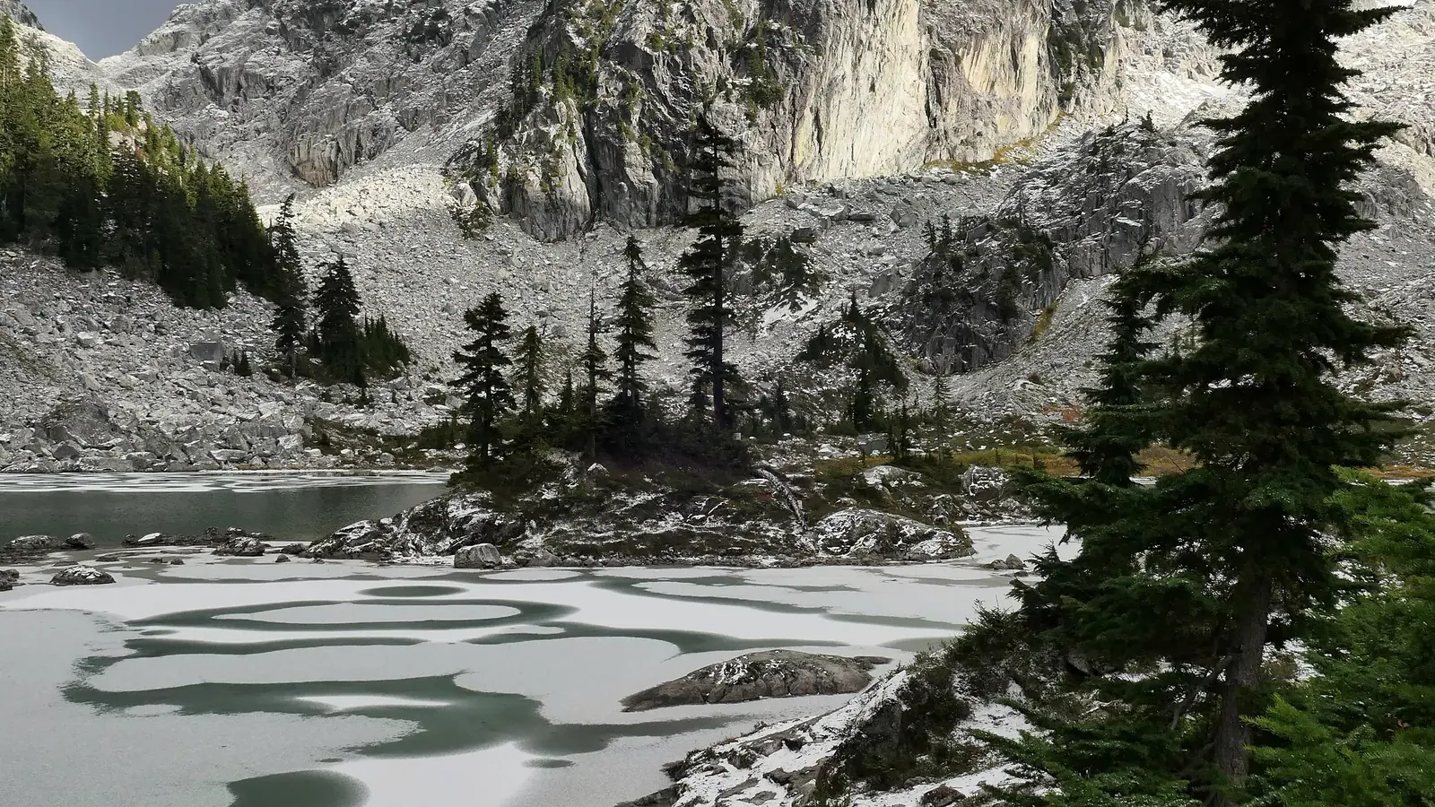 Watersprite Lake freezing over in early autumn beneath the granite walls at the head of the cirque